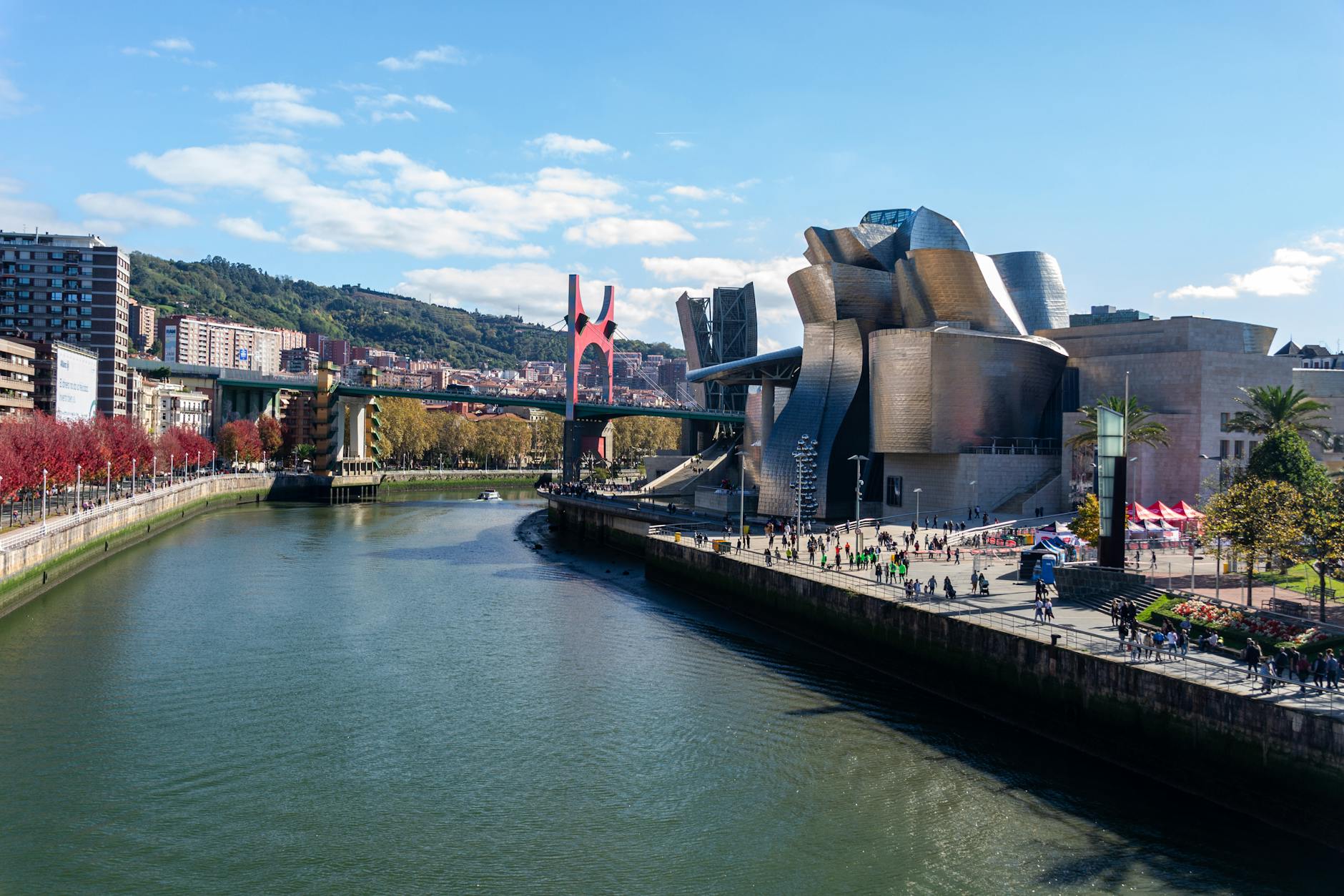 The Guggenheim Museum Bilbao with its sweeping titanium architecture alongside the Nervión River, framed by the surrounding urban landscape of the city