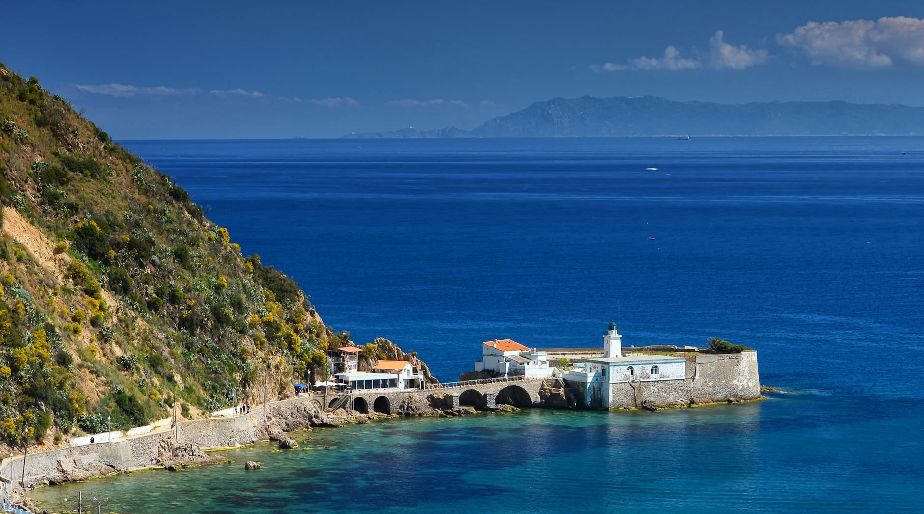Mediterranean coastal fortress overlooking vibrant blue waters and lush hillsides, evoking the ancient fortified port cities along Eastern Mediterranean cruise routes.