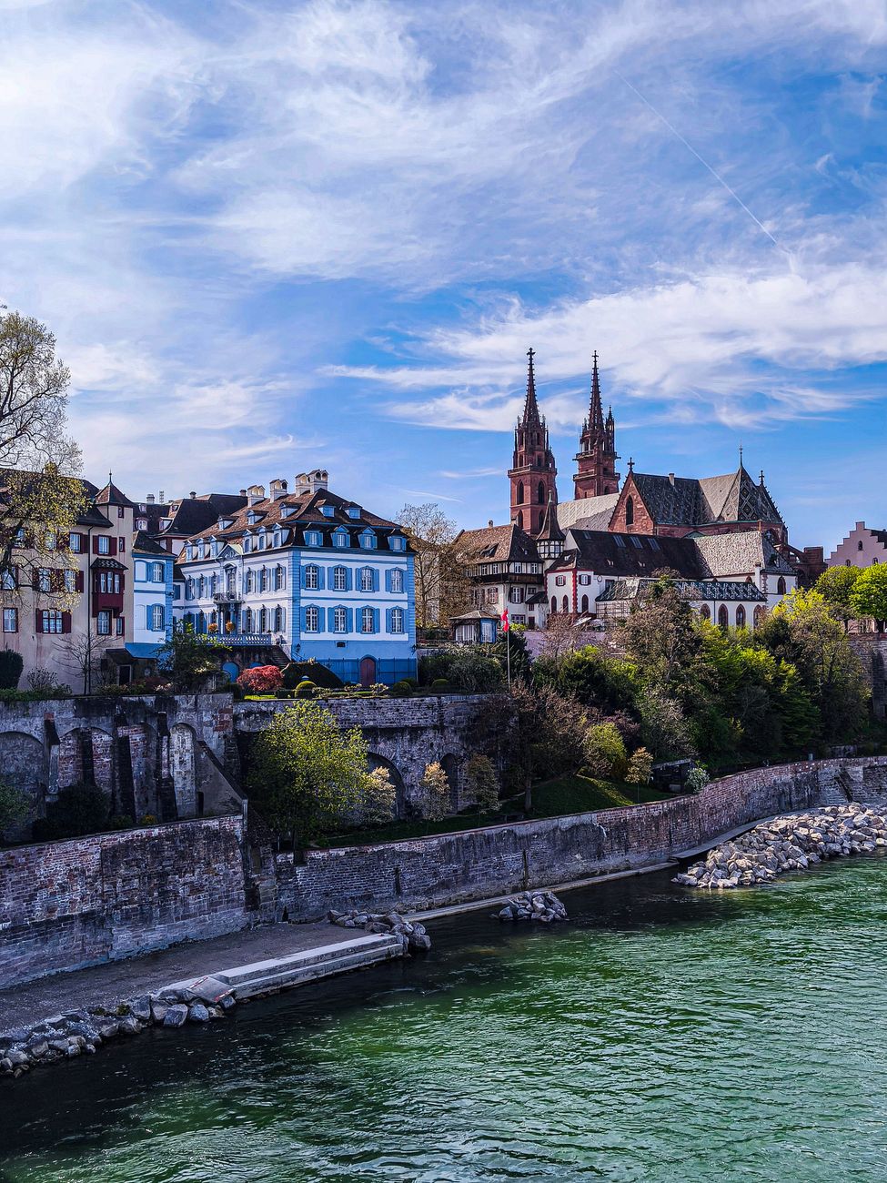 Picturesque Basel scene with historic cathedral and riverside view.