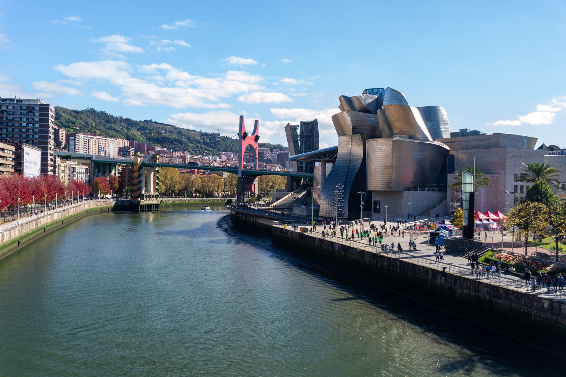 The Guggenheim Museum Bilbao with its sweeping titanium architecture alongside the Nervión River, framed by the surrounding urban landscape of the city