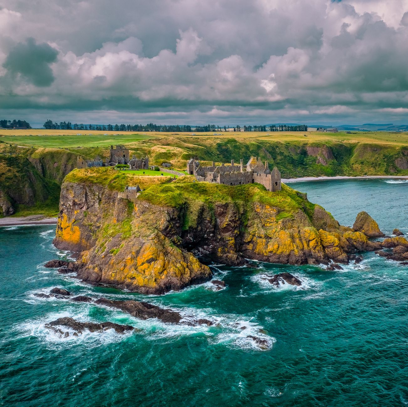 Stunning aerial view of Dunnottar Castle perched on cliffs along the Scottish coastline.