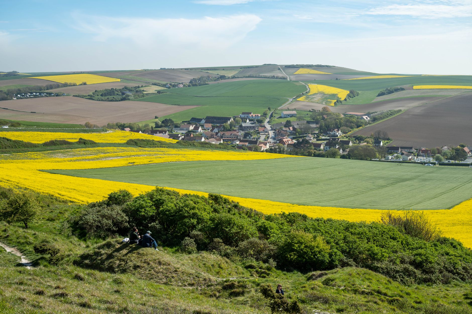 Lush green and yellow fields surround the quaint village of Escalles, France.