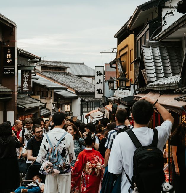 Crowded street scene in Kyoto with traditional architecture and people in kimonos.