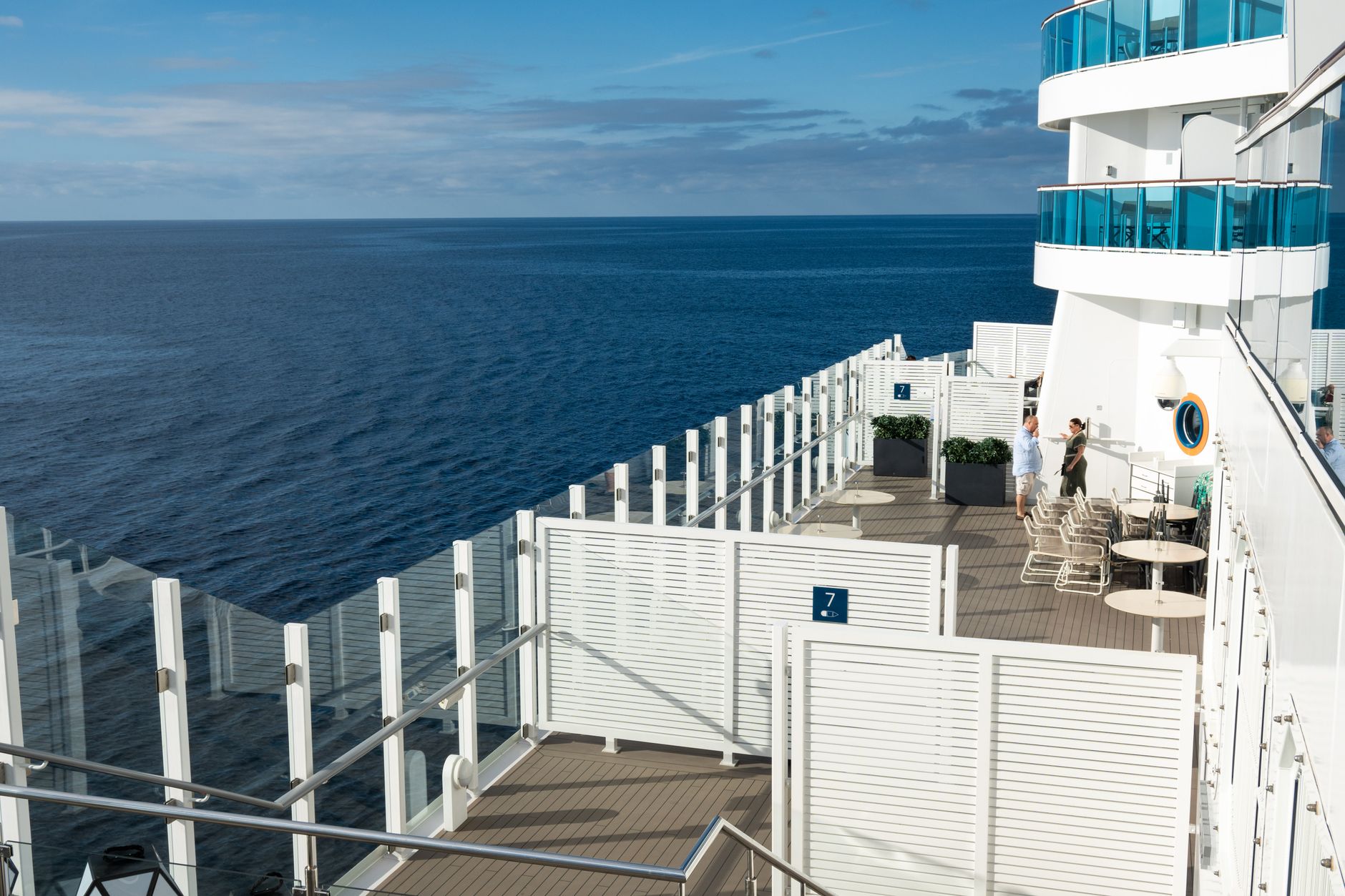 Two adults relaxing together on a cruise ship deck, enjoying a sunny ocean view — capturing the refined, unhurried atmosphere that defines the premium cruise experience discussed in this section.