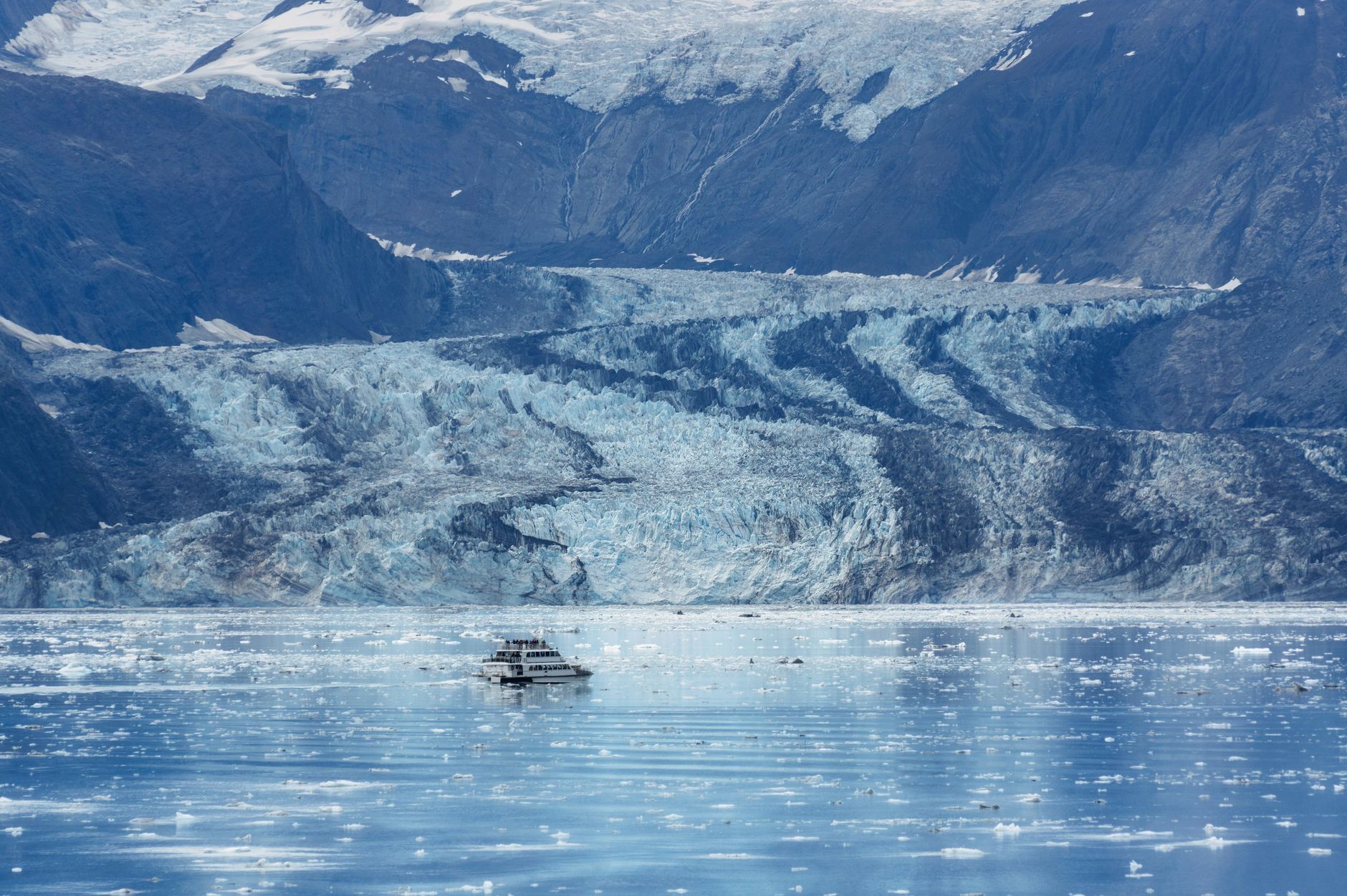 A cruise ship navigating the icy glacial waters of Alaska's College Fjord, surrounded by towering tidewater glaciers and rugged mountain terrain during a Gulf of Alaska crossing.