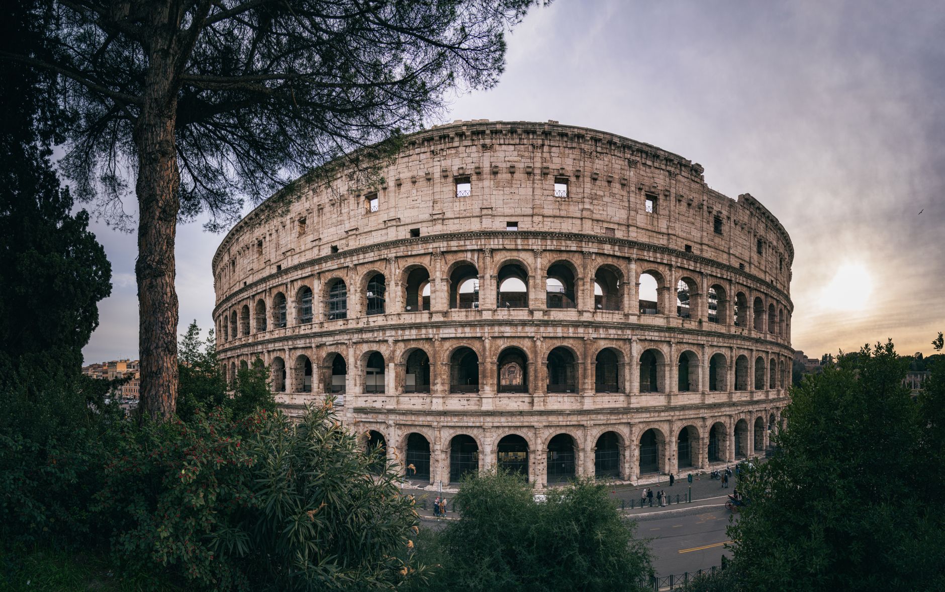 Captivating wide-angle shot of Rome's iconic Colosseum with a serene sunset backdrop.