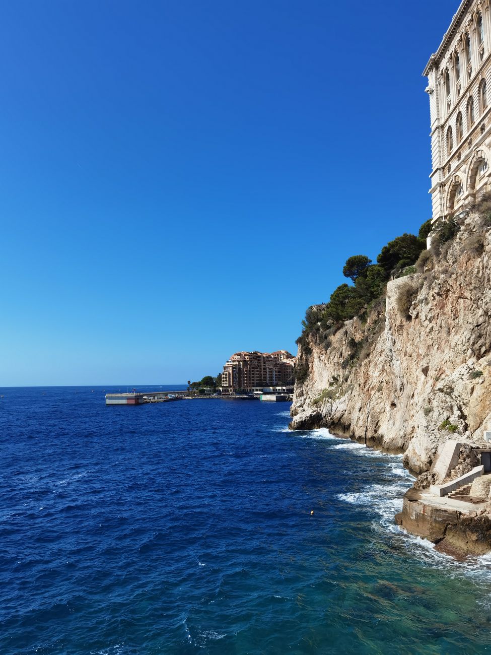 Stunning view of Monaco's rocky coast and blue Mediterranean Sea under clear skies.