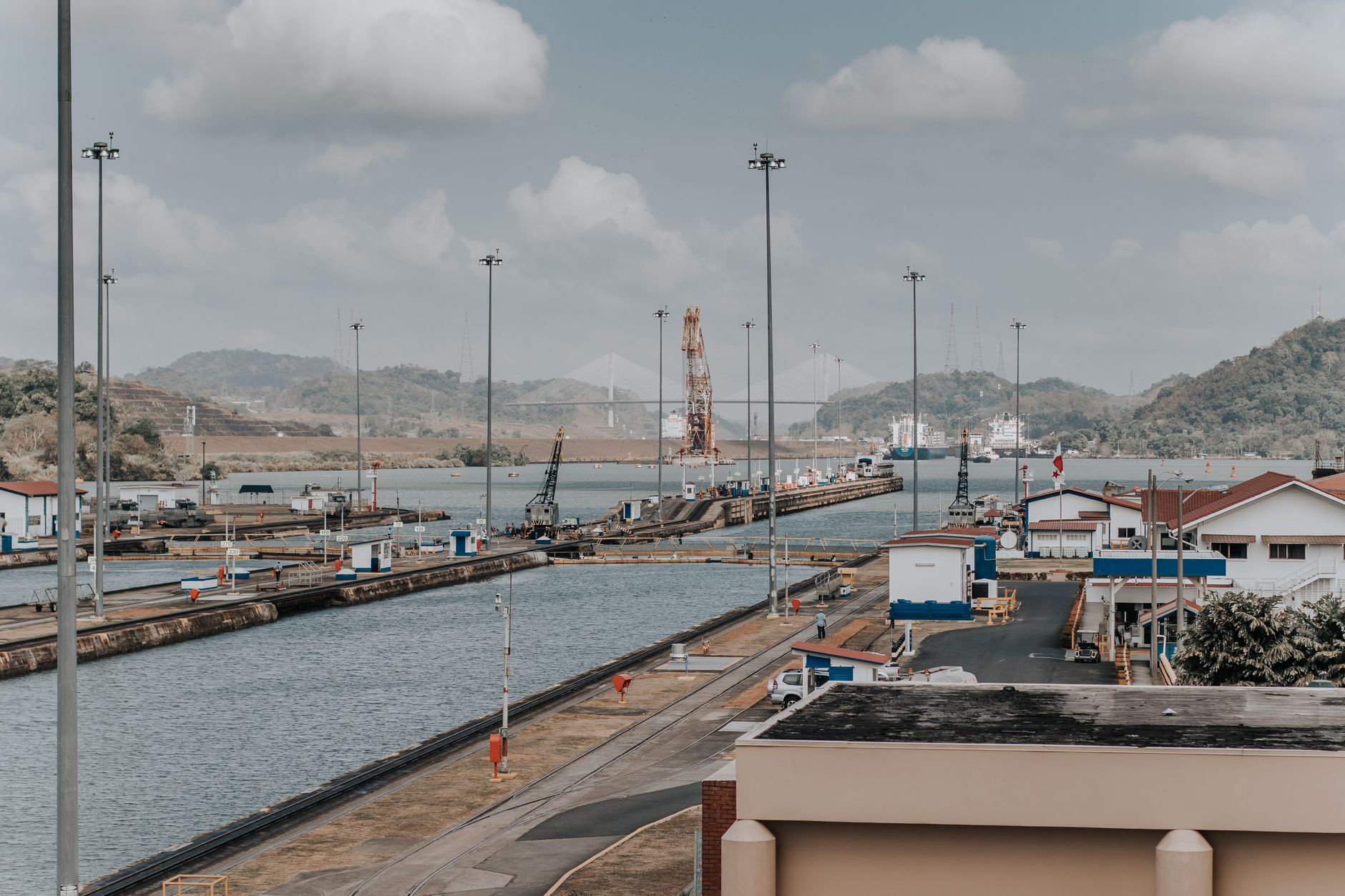 Panoramic elevated view of the Panama Canal lock chambers and surrounding maritime infrastructure, illustrating the sequential gate system ships must pass through during a full or partial canal transit.