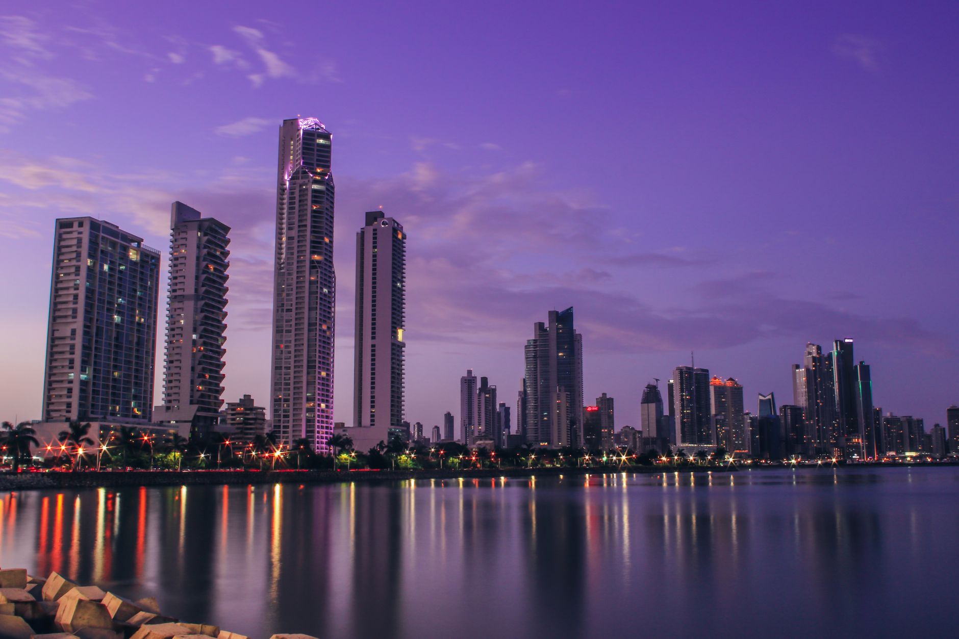 Panama City skyline with modern glass towers reflecting on the calm waters of the Bay of Panama at twilight