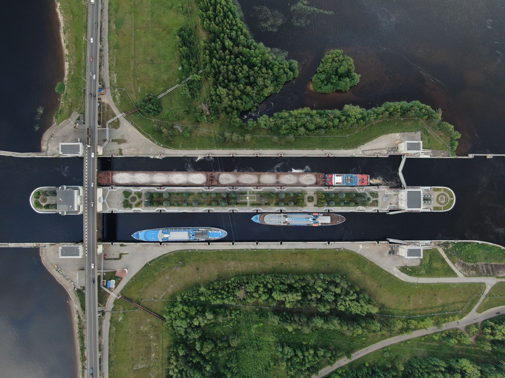 Aerial view of ships navigating through a canal lock chamber, evoking the perspective of looking down into the massive lock infrastructure during a transit day.