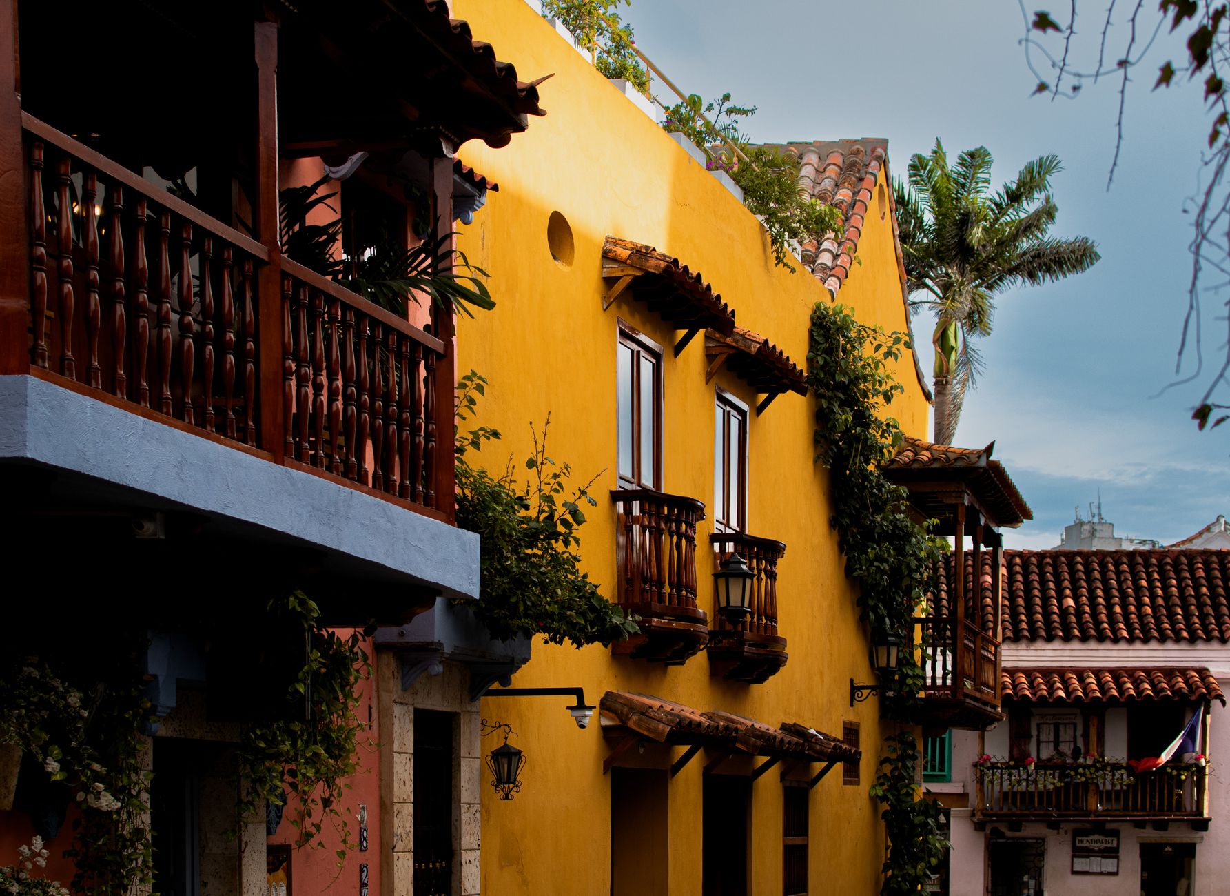 Colorful colonial facades with traditional wooden balconies line a street in Cartagena's historic walled Old City, showcasing the vibrant Caribbean architecture that greets cruise passengers at this iconic port of call.