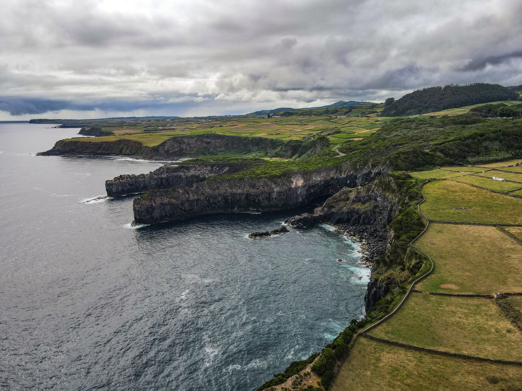 Aerial view of the dramatic volcanic coastal cliffs and lush green landscapes of São Miguel Island in the Azores, a popular mid-Atlantic port of call on transatlantic repositioning cruises from New York.