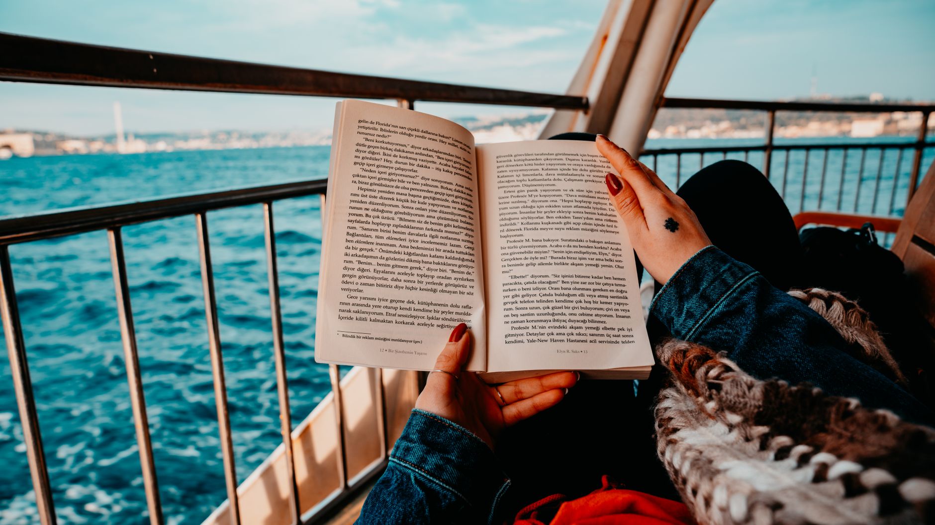 A person reading a book aboard a boat on the water, evoking the quiet solitude of a sea day spent with a good read — the kind of unhurried pace that defines whether this route is right for you.