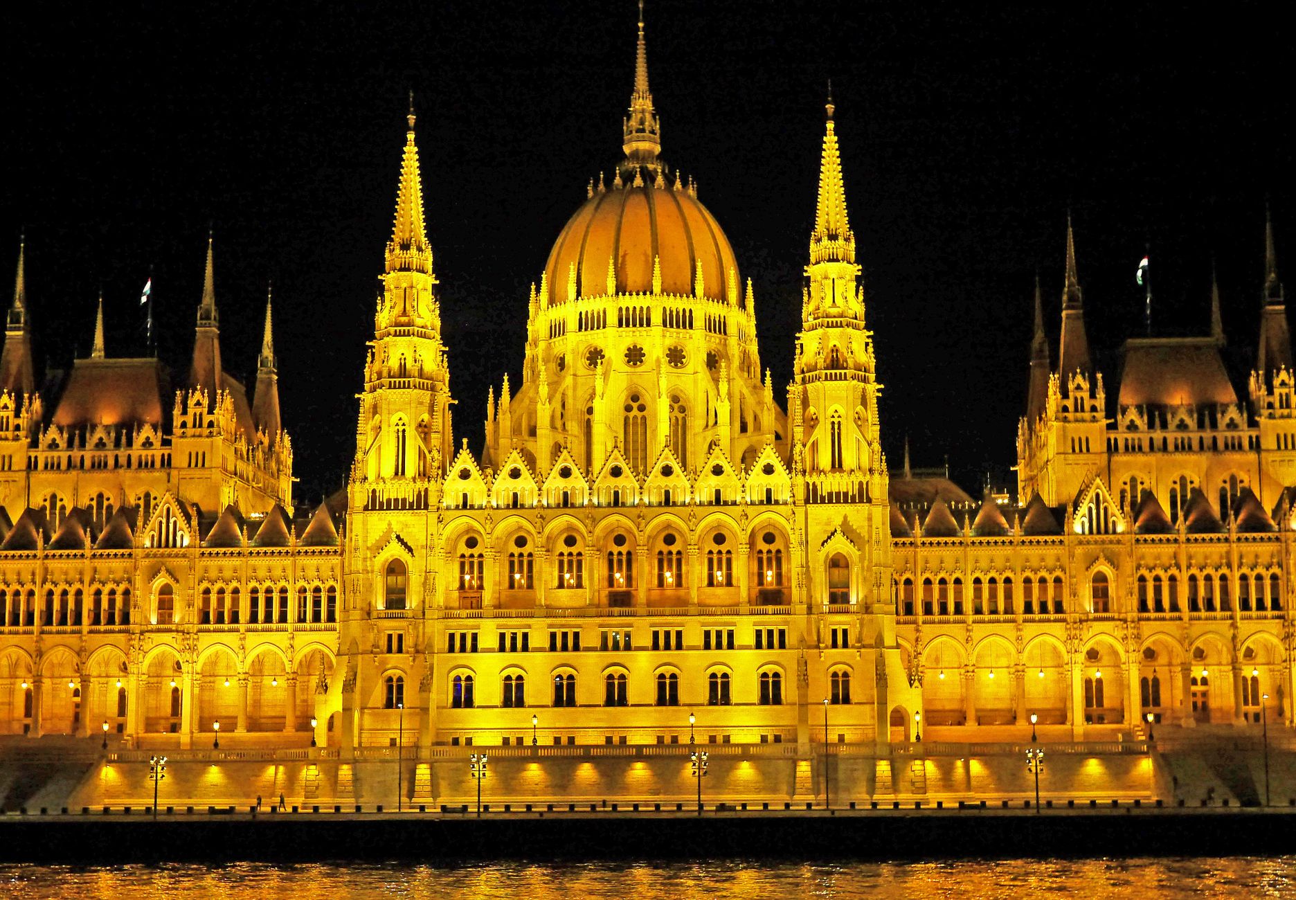 The illuminated Hungarian Parliament Building glows at twilight with its reflection shimmering on the Danube River, a landmark sight along European river cruise routes from Bucharest to Budapest.