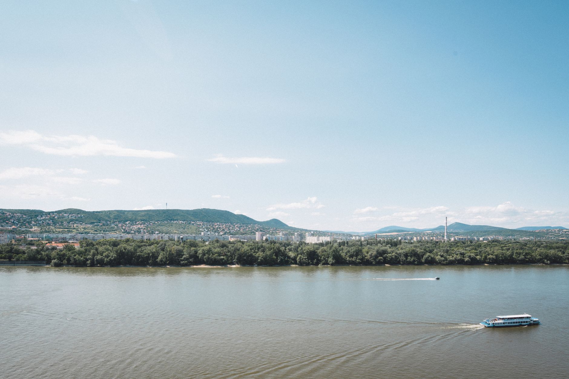 The Danube River stretching into the distance with a sweeping panoramic perspective, evoking the scenic waterway route from Bucharest through southeastern Europe.