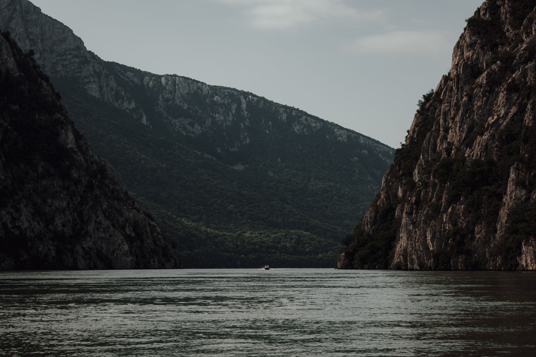 The Danube River flowing through the Iron Gates gorge in Romania, with dramatic steep cliffs rising on both sides of the calm water