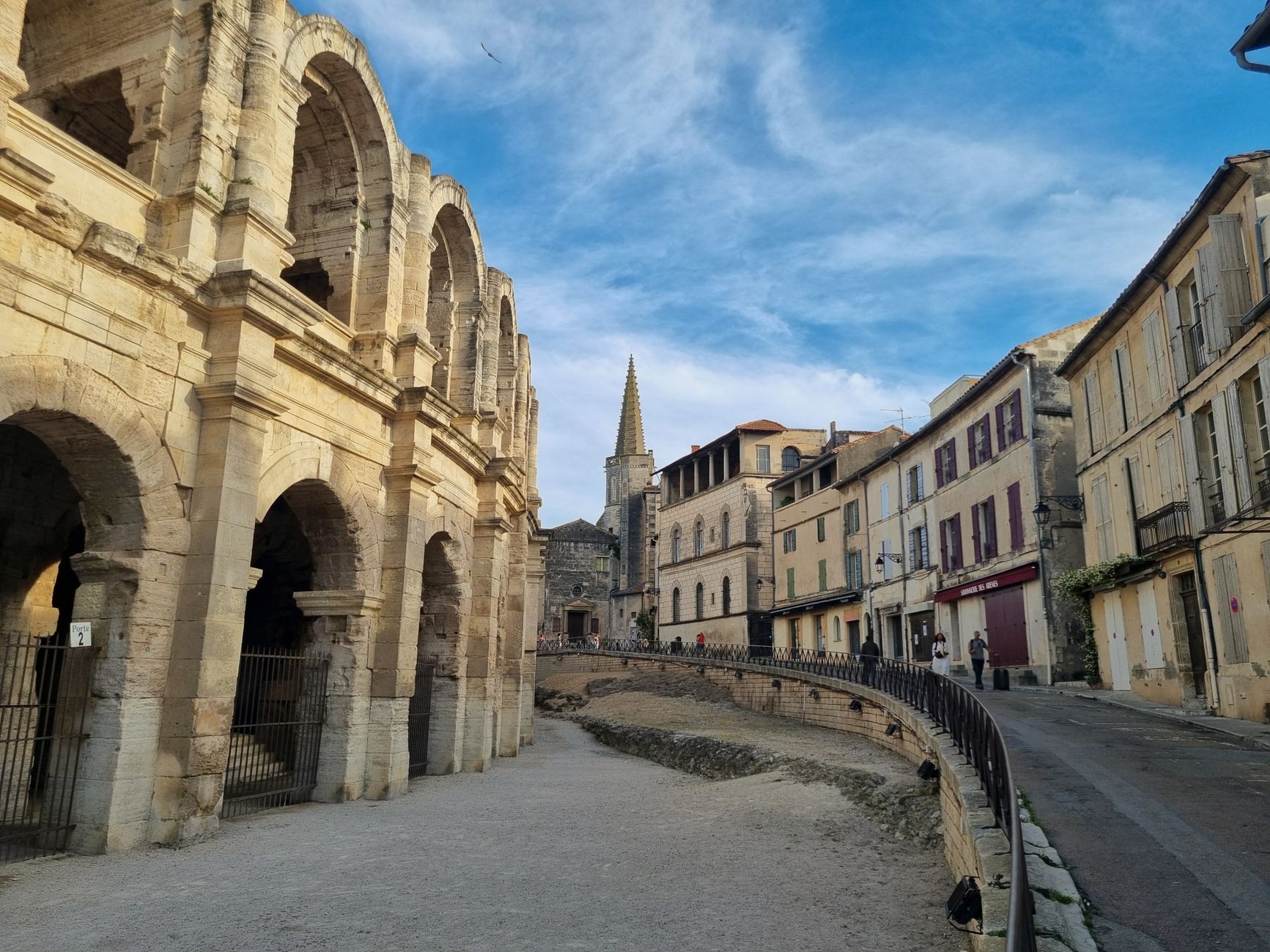 The Roman Amphitheatre of Arles rises above a charming Provençal street scene with ochre-toned buildings, capturing the historic heart of this Rhône river cruise port of call.