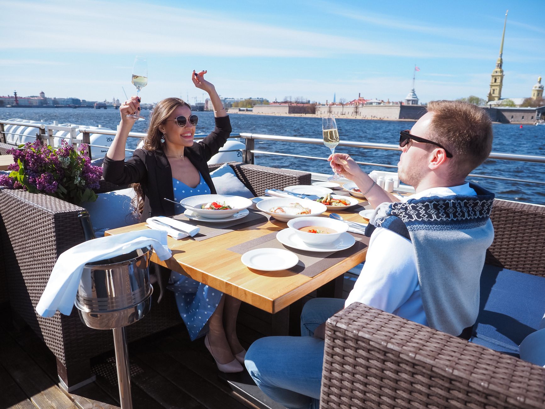 A couple dining aboard a cruise boat with a scenic riverside view, evoking the intimate onboard dining experiences that distinguish different river cruise lines.