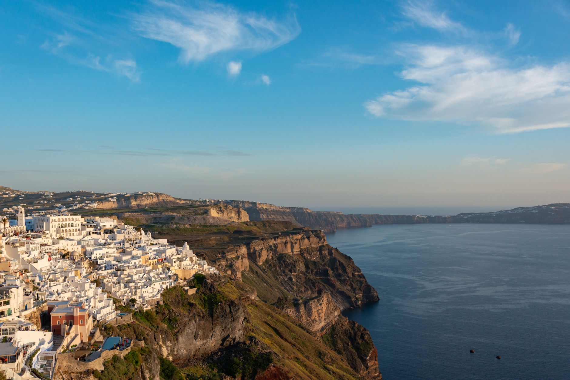 Whitewashed clifftop buildings of Santorini cascading down the caldera edge above the deep blue Aegean Sea