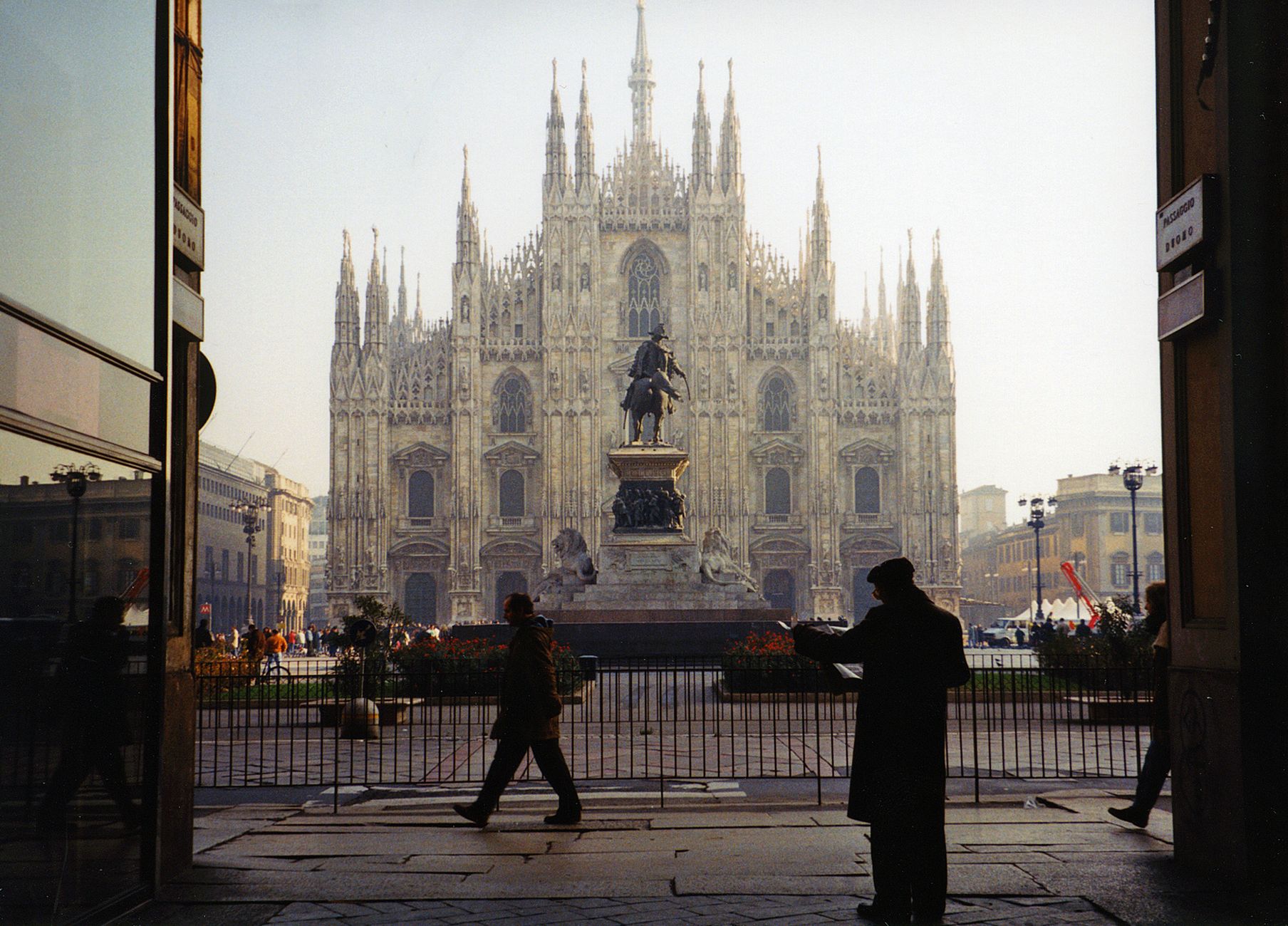 Milan's iconic Duomo cathedral rising majestically above the piazza as silhouetted pedestrians traverse the square in the foreground