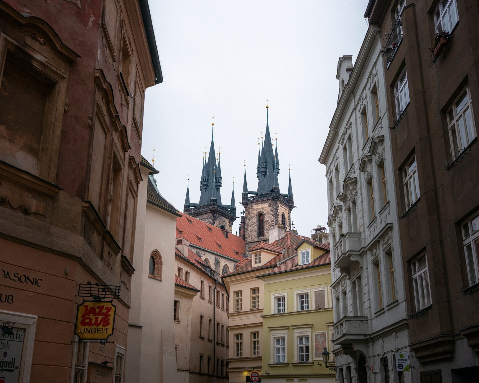 Gothic church spires rise above Prague's historic Old Town, framed by traditional European architecture and layered Baroque rooftops