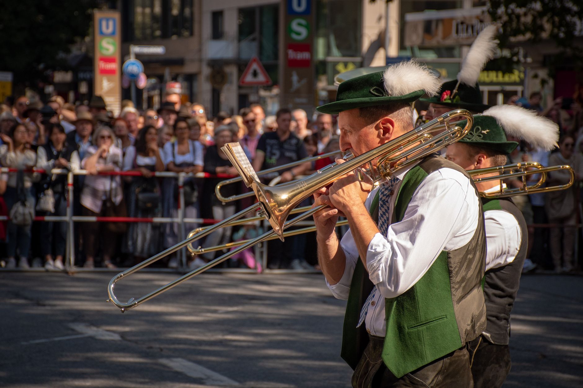 Musicians in traditional Bavarian attire playing trombone during a vibrant street festival in Germany, evoking the intimate riverside celebrations that make small towns like Vilshofen a charming alternative to larger cities