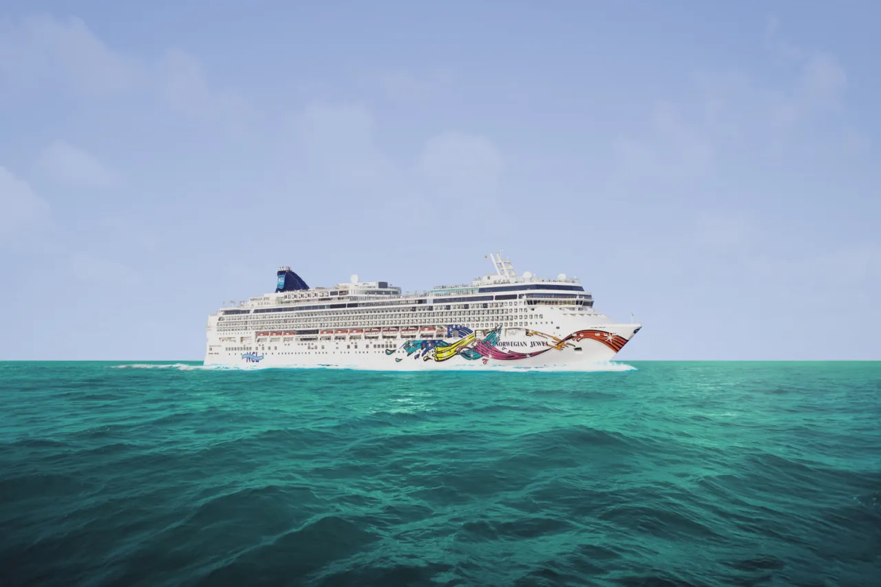 Norwegian Jewel cruise ship sailing across open ocean with dramatic sky and deep blue water under aerial perspective.