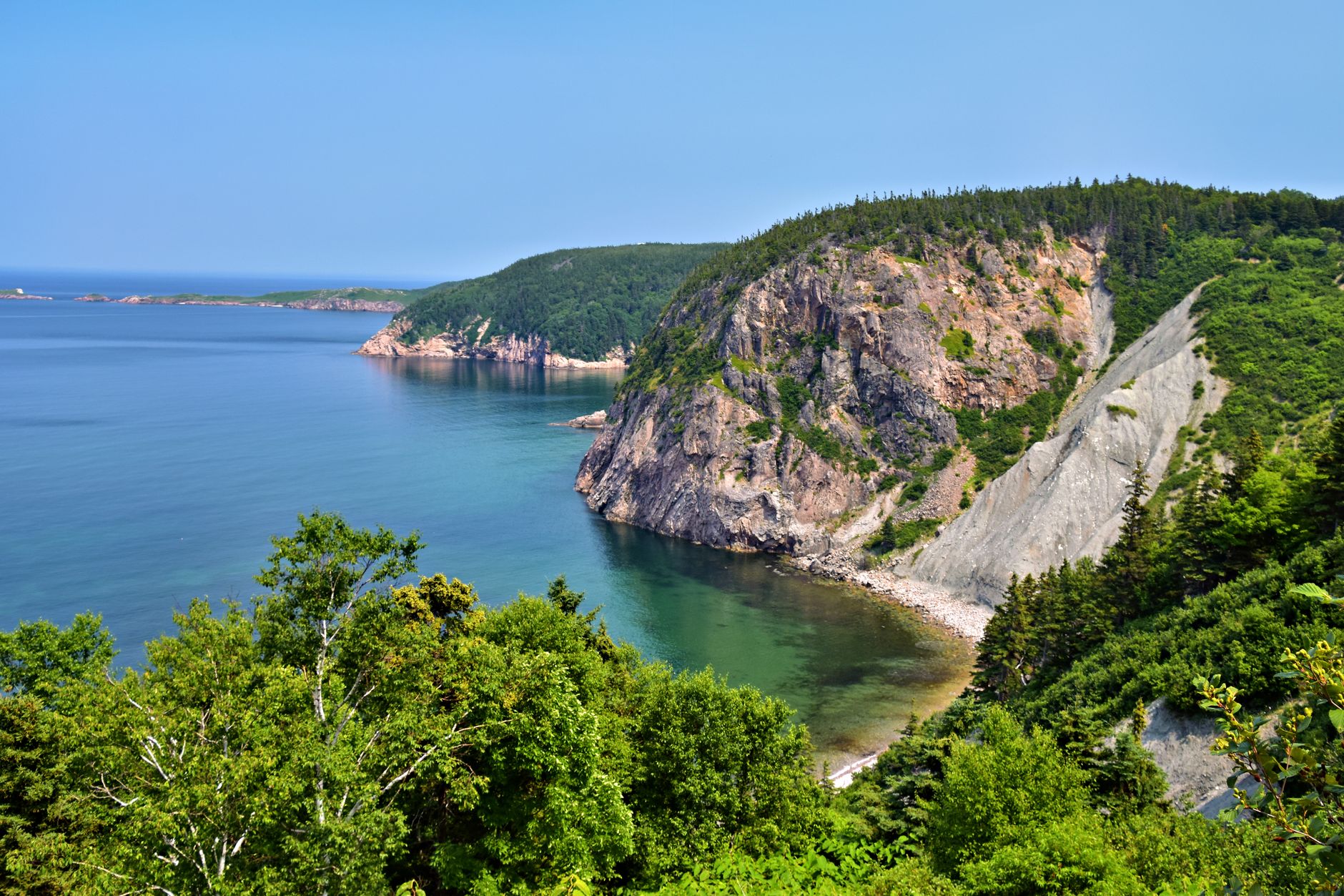 Cape Breton's dramatic Atlantic coastline featuring lush green headlands and towering ocean cliffs along Nova Scotia's maritime route