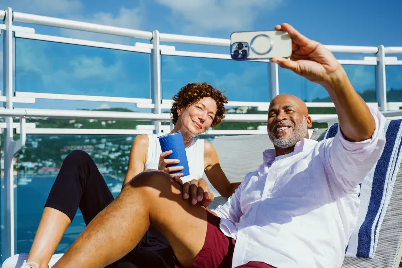 Passengers relax in lounge chairs on the deck of Princess Cruises' Enchanted Princess with ocean horizon visible.