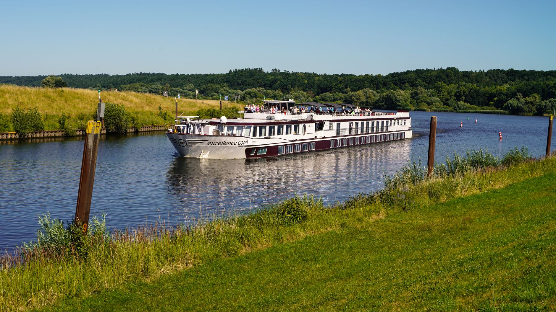 A cruise ship navigates a narrow German canal in Artlenburg, illustrating the intimate scale of European waterway cruising compared to open-ocean voyages.