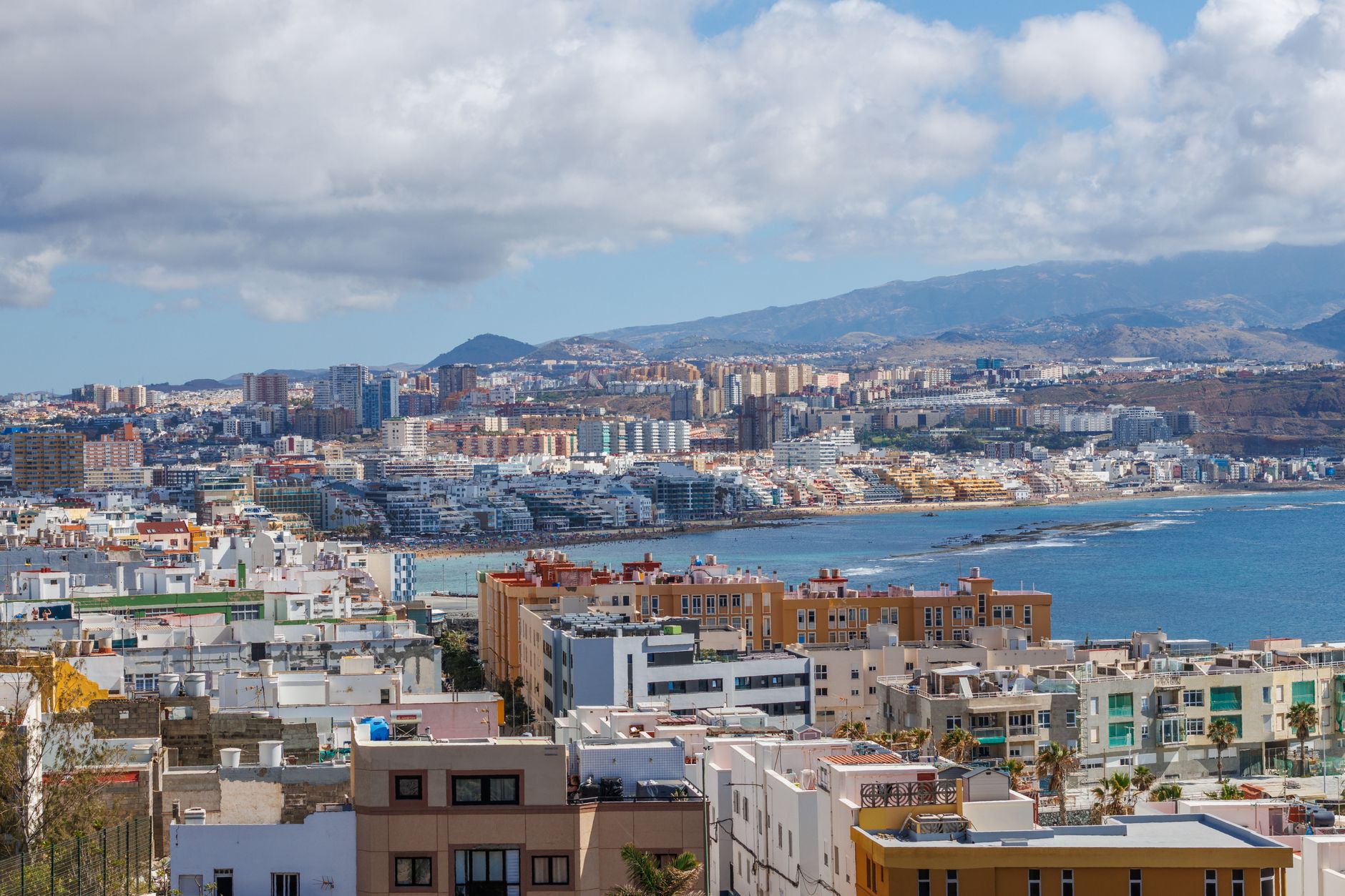 Las Palmas de Gran Canaria's cityscape and harbour stretching along the coastline beneath clear blue skies, a typical Canary Islands port call on Atlantic cruise itineraries.
