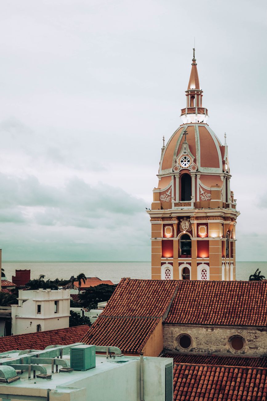 A stunning view of the dome of a cathedral in Cartagena, Colombia with a scenic ocean backdrop.
