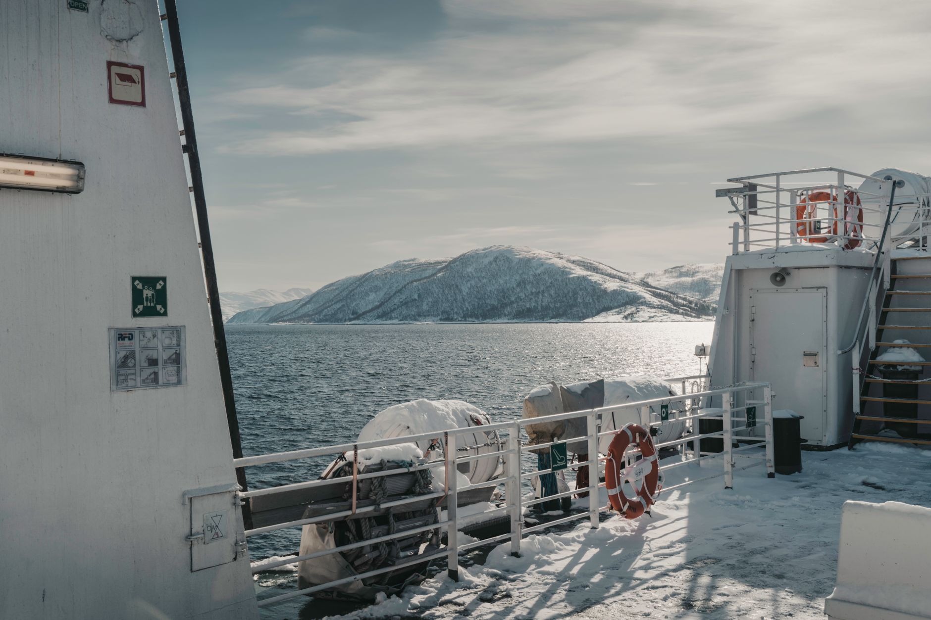 View from a ferry navigating Norway's calm coastal waters flanked by snow-covered mountains — evoking the intimate, immersive fjord experience that Bergen departures offer expedition-minded travelers.