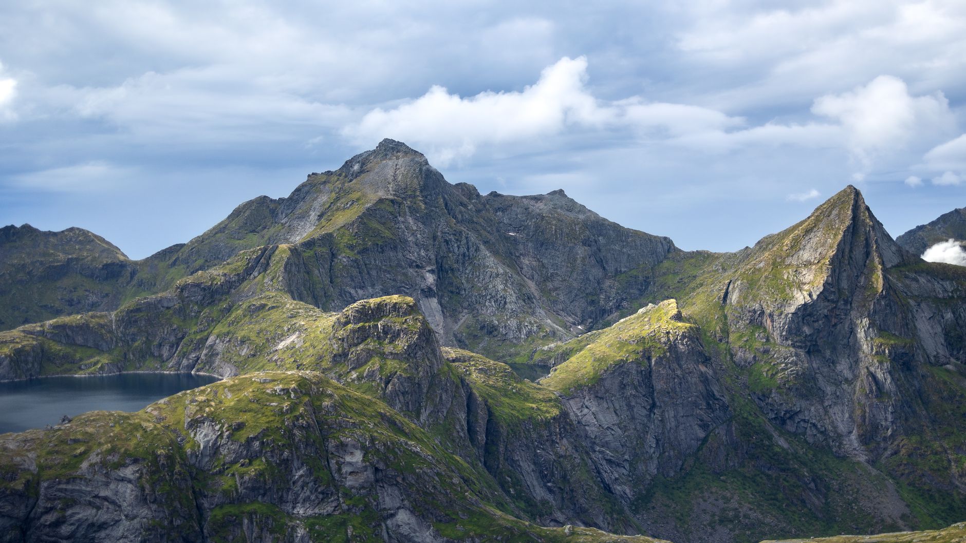 Jagged Lofoten mountain peaks rise dramatically against a sweeping, cloud-filled sky in Nordland, northern Norway