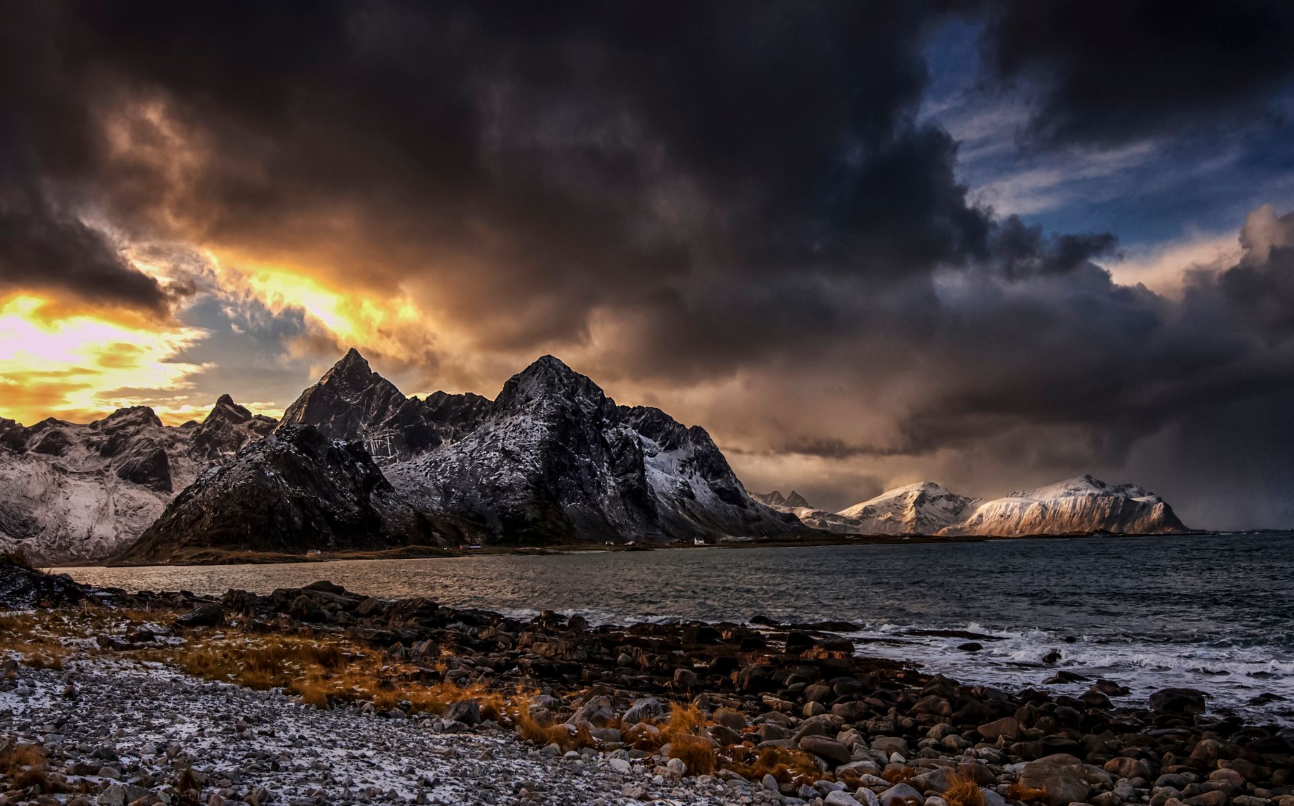 Dramatic Nordic mountains and rugged coastline bathed in warm sunset light along Norway's coastal route