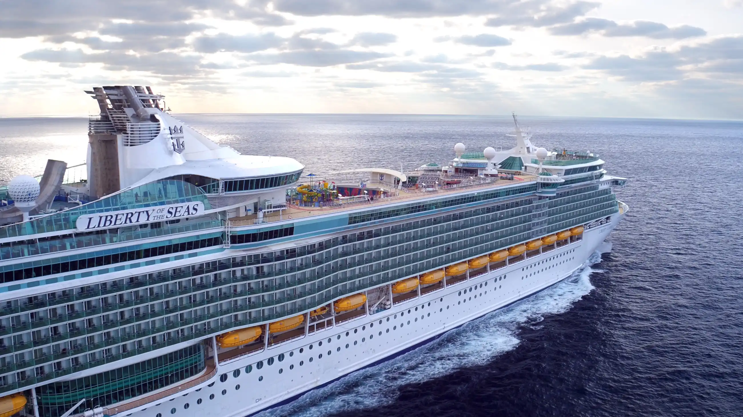Aerial drone view of Royal Caribbean's Liberty of the Seas underway in open ocean under partly cloudy skies.
