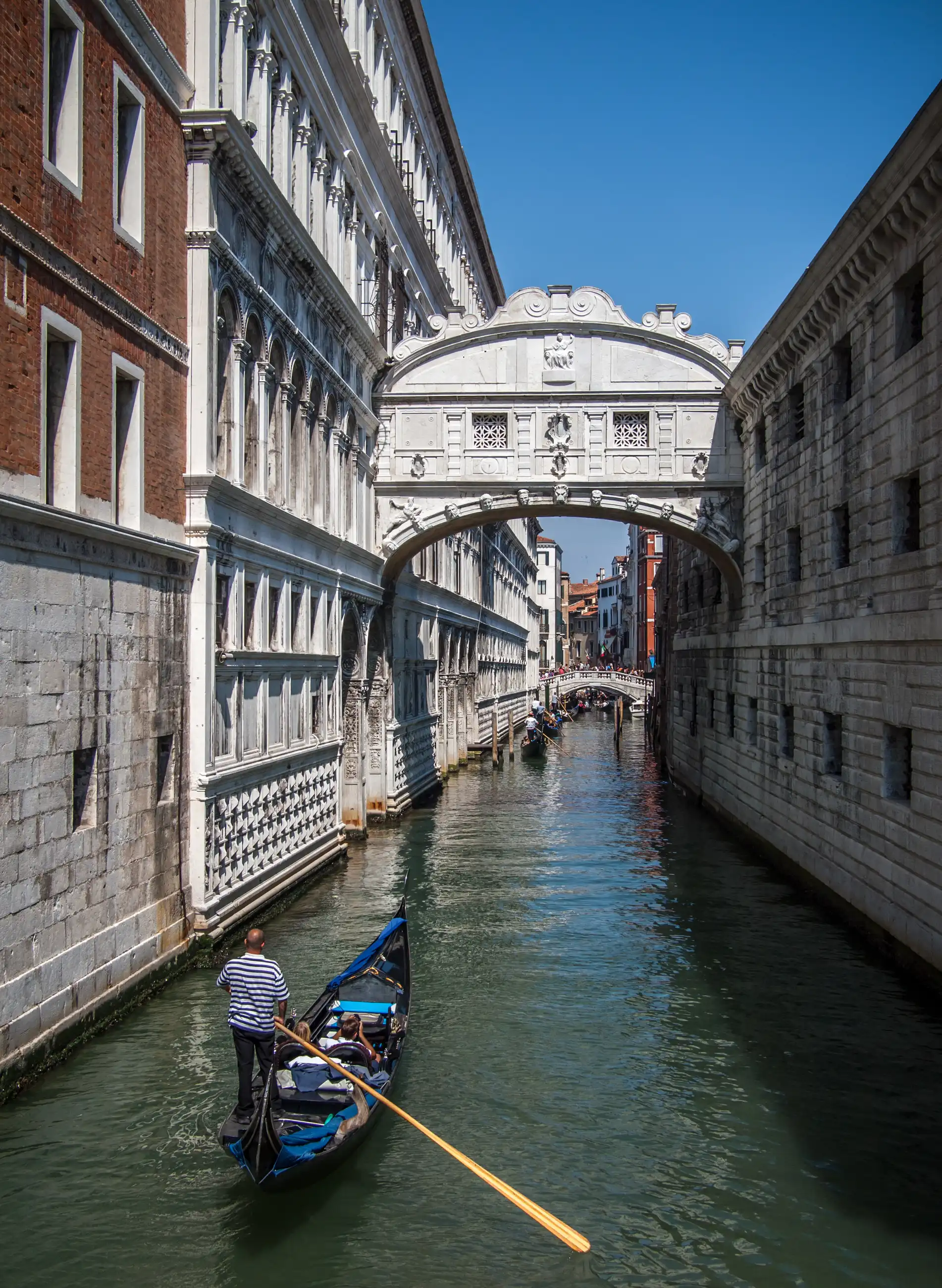 A gondola passes beneath Venice's Bridge of Sighs on the Rio di Palazzo, framed by Renaissance palace façades.