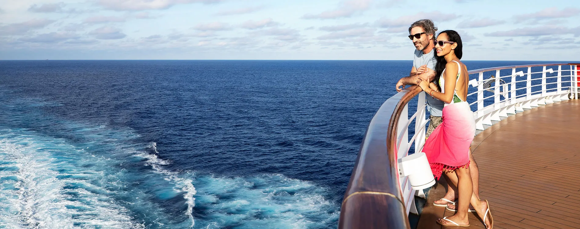 Couple enjoying ocean view from cruise ship deck on sunny day
