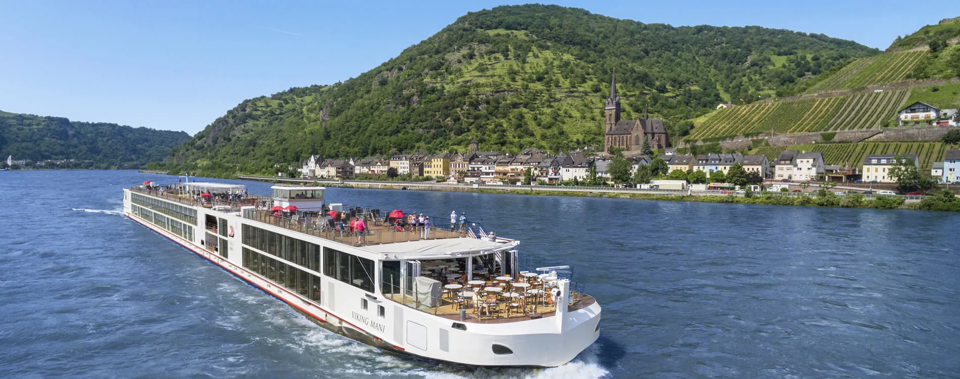 River cruise ship sailing past vineyards and historic town along scenic river