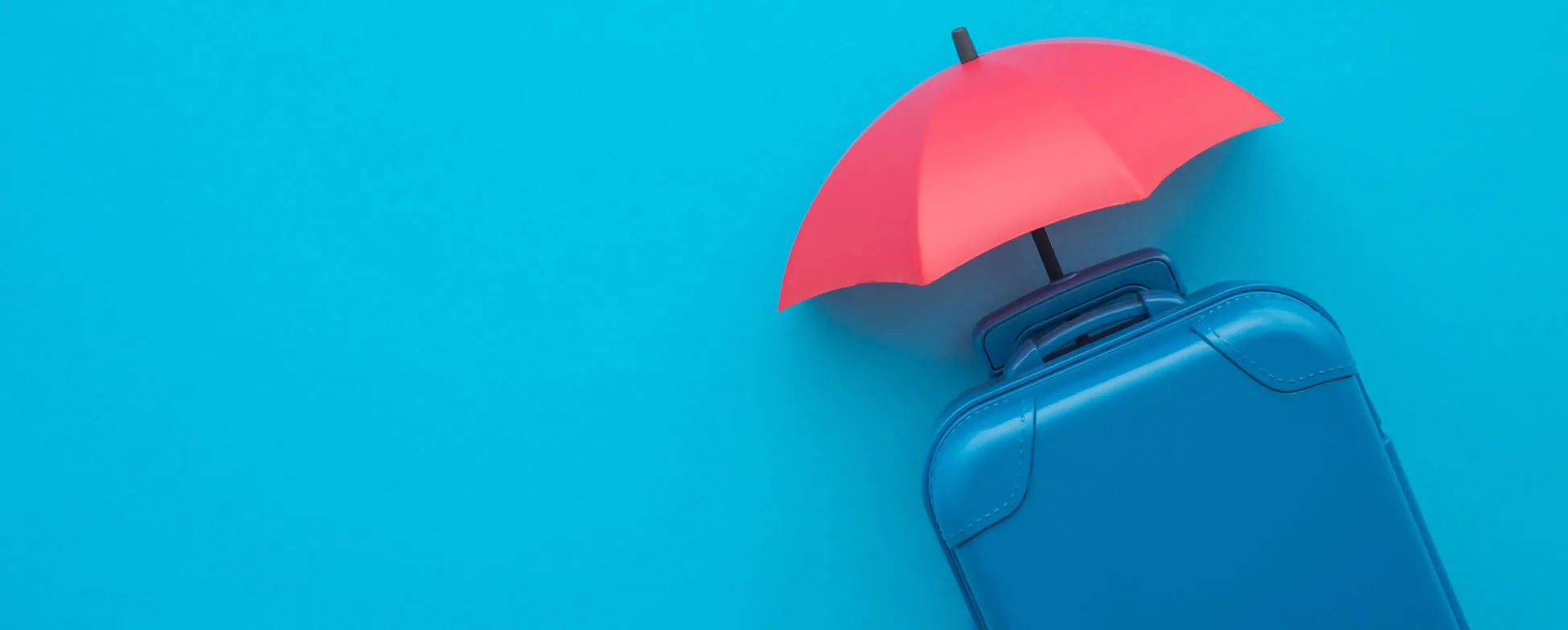 Blue suitcase with red umbrella on vibrant turquoise background