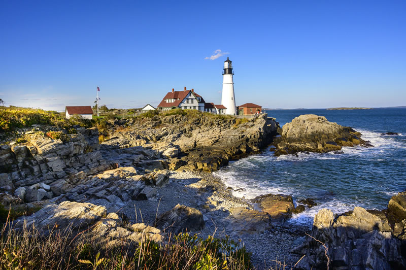 Portland Head Lighthouse on rocky Maine coastline with blue ocean waves
