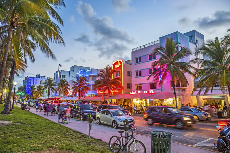 Vibrant Miami Beach Ocean Drive at twilight with colorful hotels and palm trees