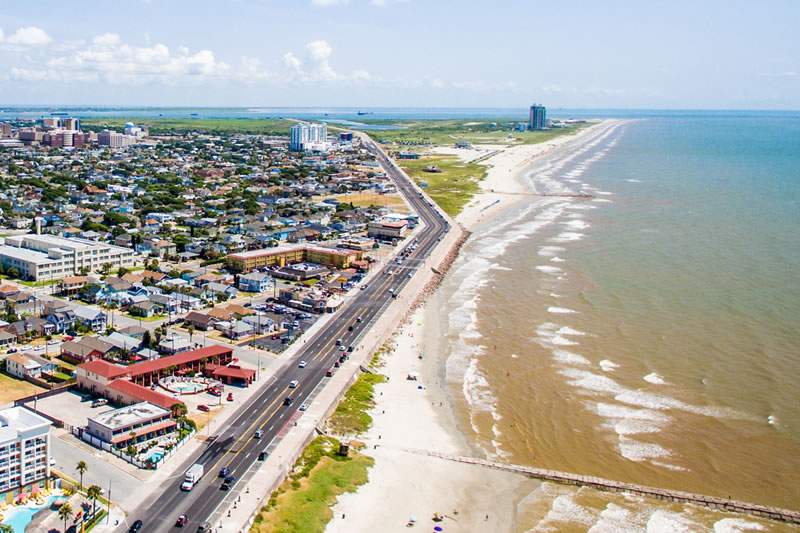 Aerial view of coastal city with beach, road, and dense urban landscape