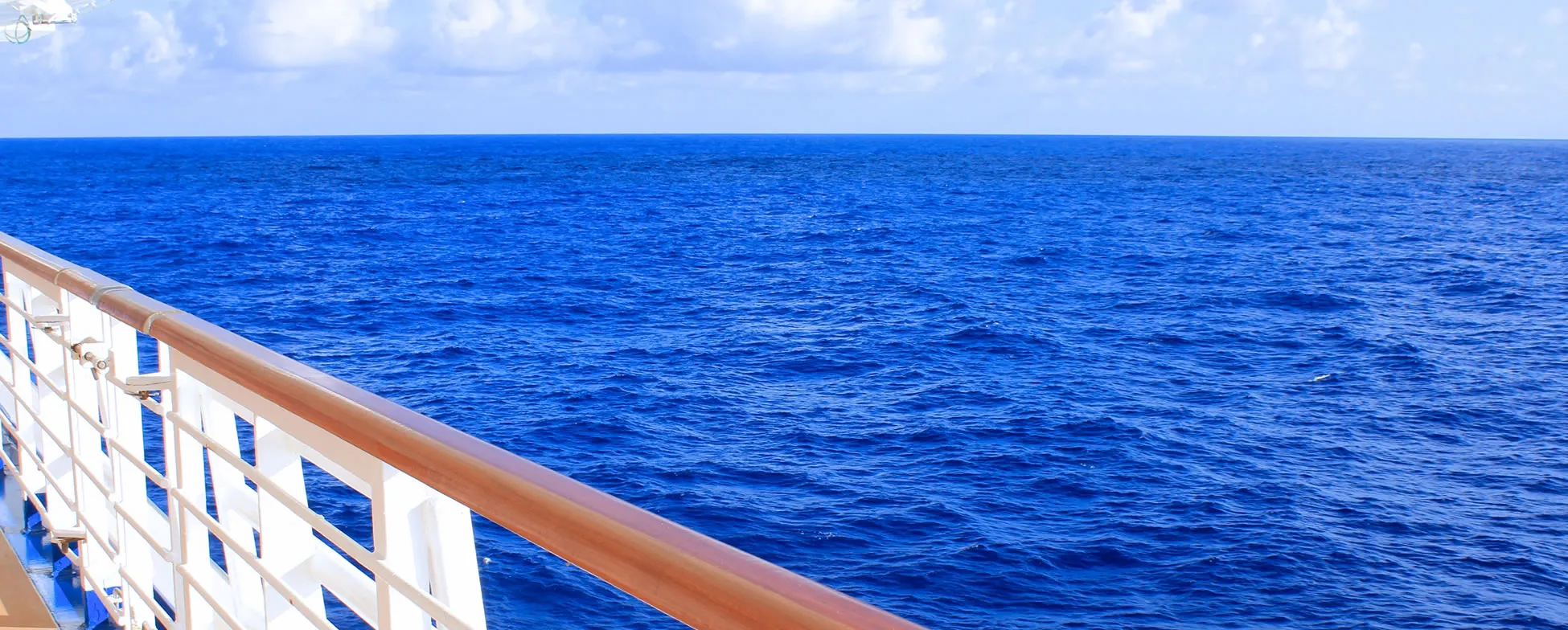 View of deep blue ocean from cruise ship deck with white railing