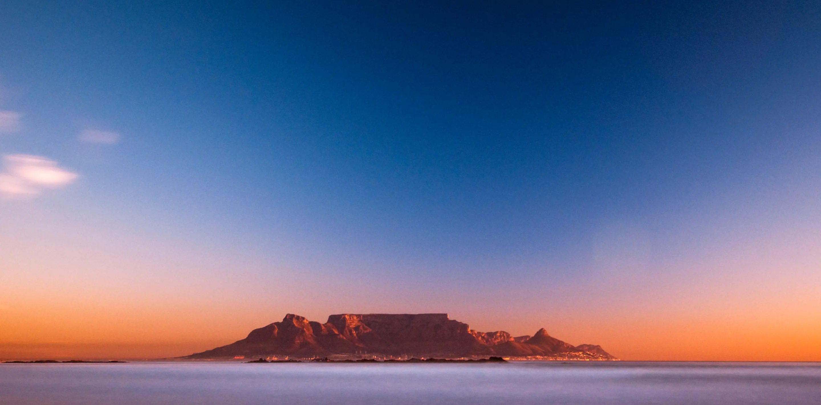 Das Meer und der Tafelberg von Kapstadt in der Ferne bei Sonnenuntergang.