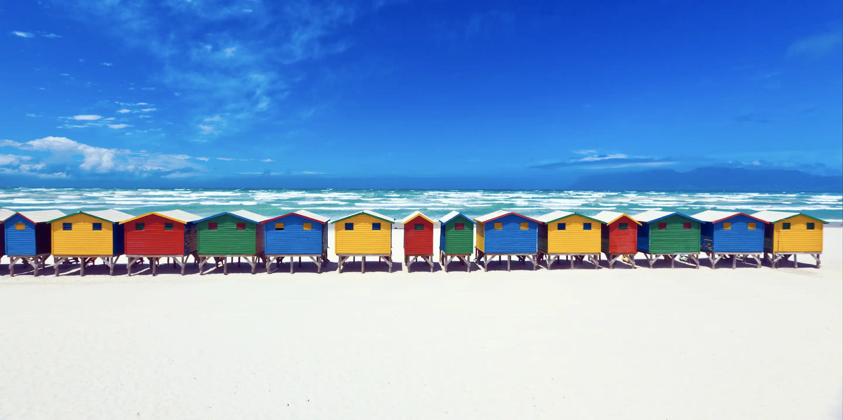 Bunte Hütten in einer Reihe am Strand.