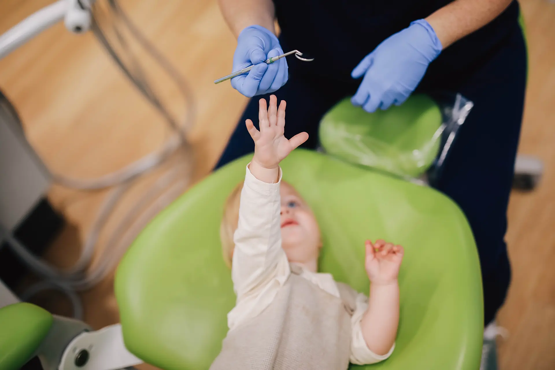 Baby reaching up in the dental chair, preventive pediatric dentistry