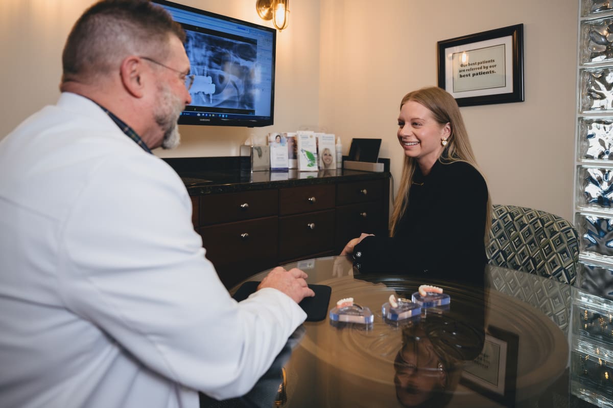 Dentist showing dental implant model to patient during consultation