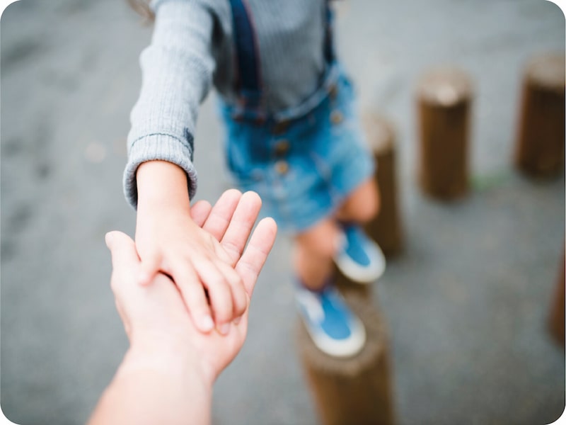 Niño de la mano de una persona en equilibrio.