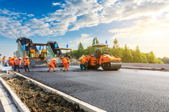 Construction site is laying new asphalt road pavement,road construction  workers and road construction machinery scene. Photos | Adobe Stock
